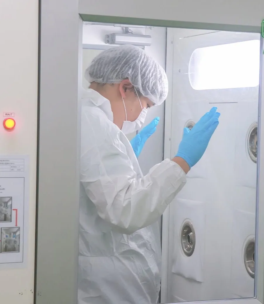 Staff in cleanroom suit using the air shower before entering production